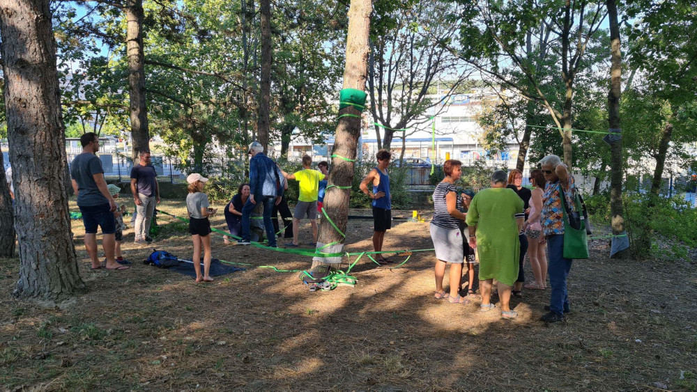 Medzi stromami v záhrade ÚNSS sú natiahnuté laná a veľa nich v sa rozprávajú inštruktori Slackline spolu s účastníkmi 