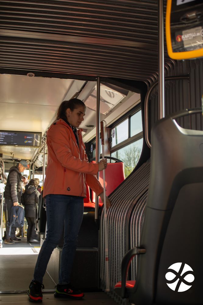 Mladá žena s bielou palicou rukami prehmatáva spoj vo vnútri autobusu tzv. kĺb. 