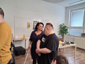 Dvaja klienti spolu s vedúcou Krajského strediska sa učia priestorovej orientácii s orientačnou palicou. 