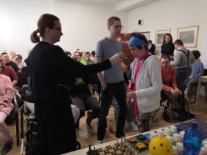 Sociálna pracovníčka prikladá color tester na svetlý sveter klientky, pri nej stojí chlapec, ktorý čaká na priloženie color testeru na jeho odev. 