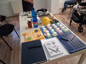 Na obdĺžnikovom stole sú rozložené optické a kompenzačné pomôcky. 